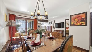 A dining area with a wooden table set for four, a chandelier, and a painting on the wall. - Vail Condo w/ Pool, Hot Tub & Free Bus Access (Vail)