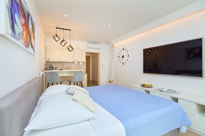 Un dormitorio moderno con cama, escritorio y televisor.