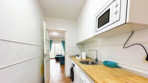 A kitchen with white cabinets, a wooden countertop, a dishwasher, and a microwave. - GUA001 (Ayamonte)