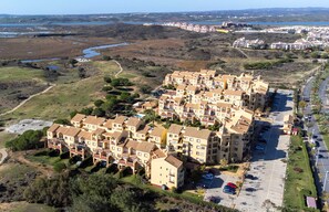 Un quartier résidentiel composé d’une rangée d’immeubles à plusieurs étages, d’un parking et, au loin, d’une rivière.