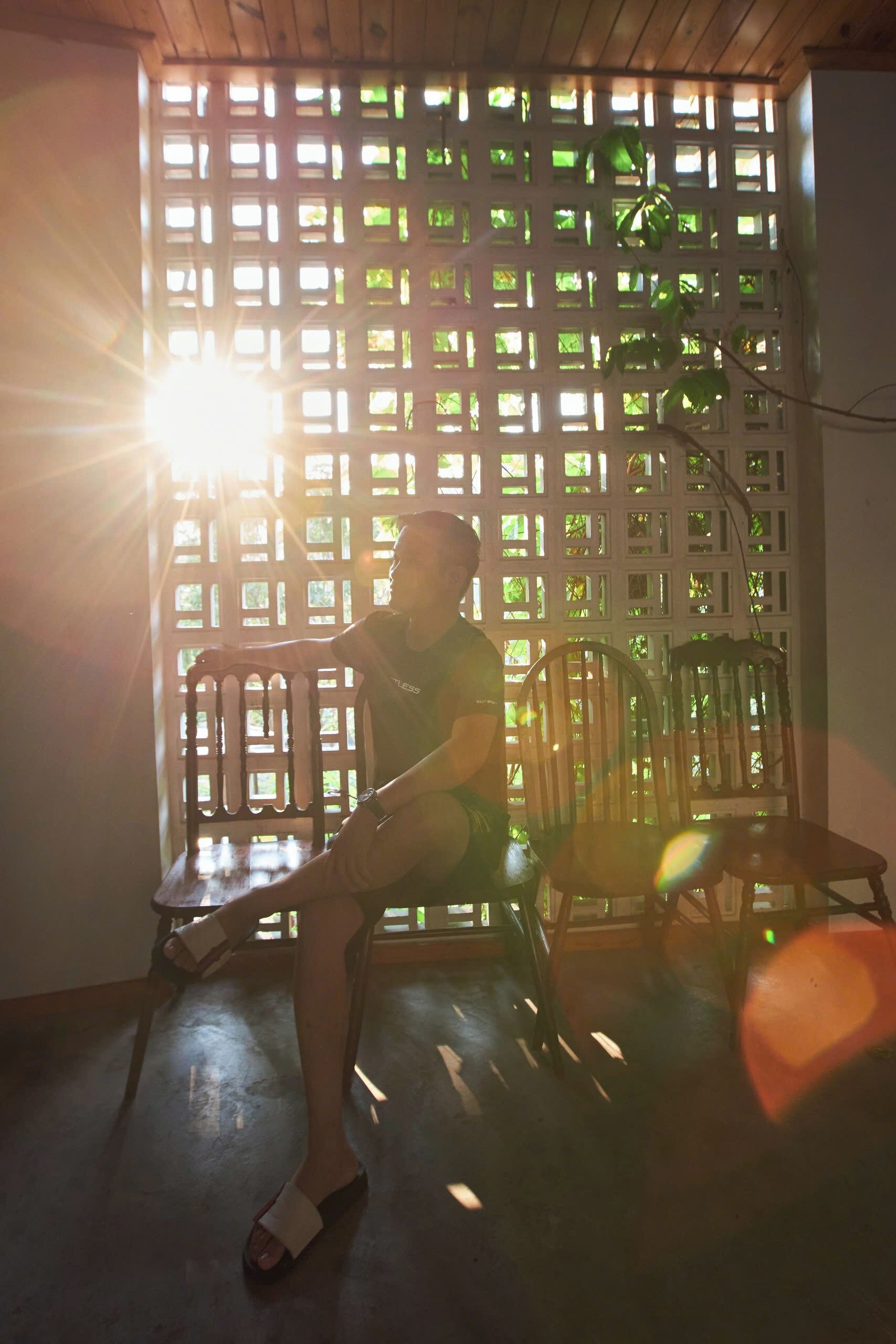 A person sitting on a chair in a room with a wooden floor and a lattice partition.