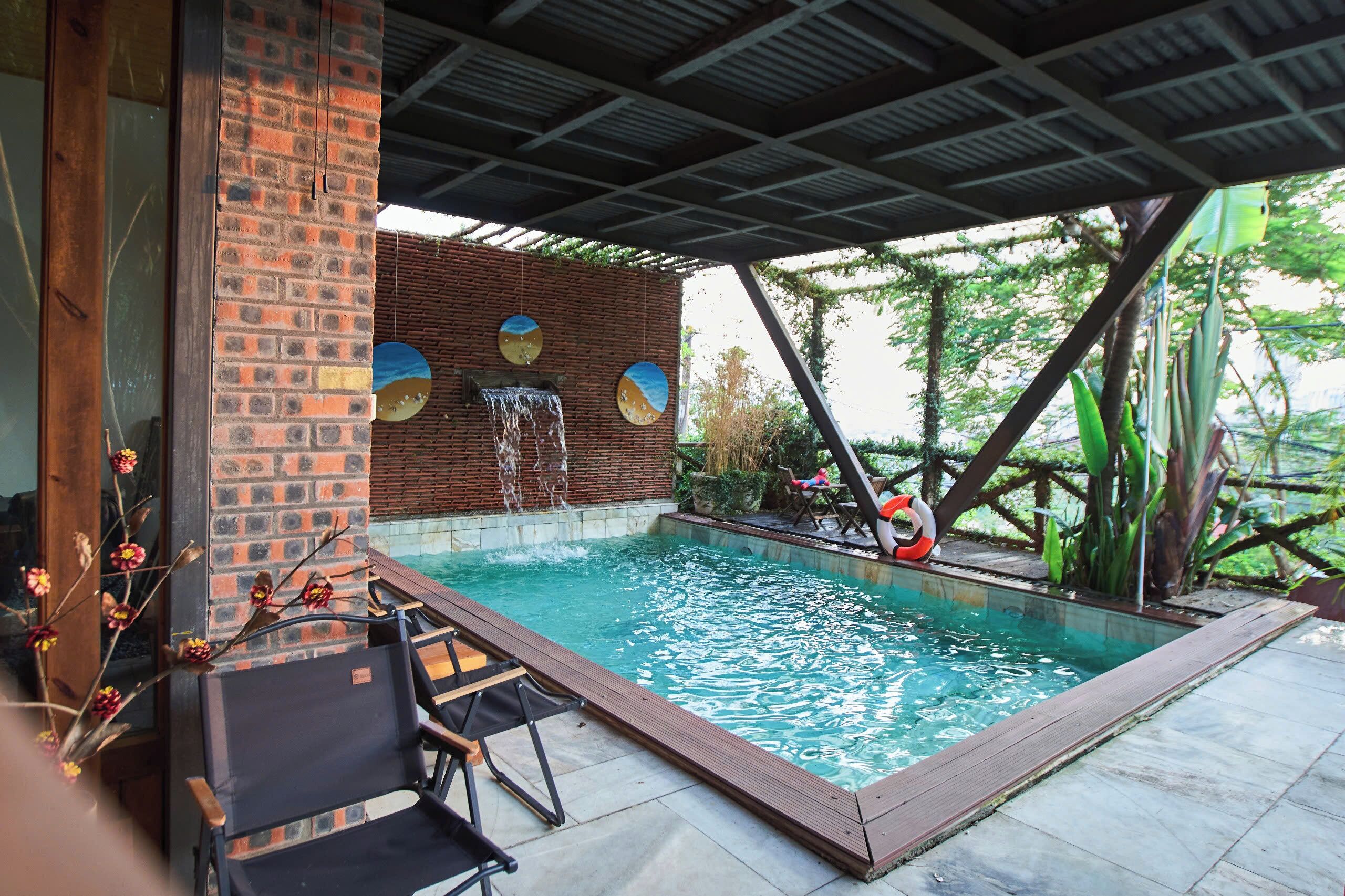 A swimming pool with a brick wall, a wooden deck, and lounge chairs.