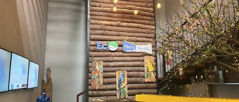 A rustic interior with a wooden wall, a yellow counter, and a sign reading "MAY'S TRAVEL".