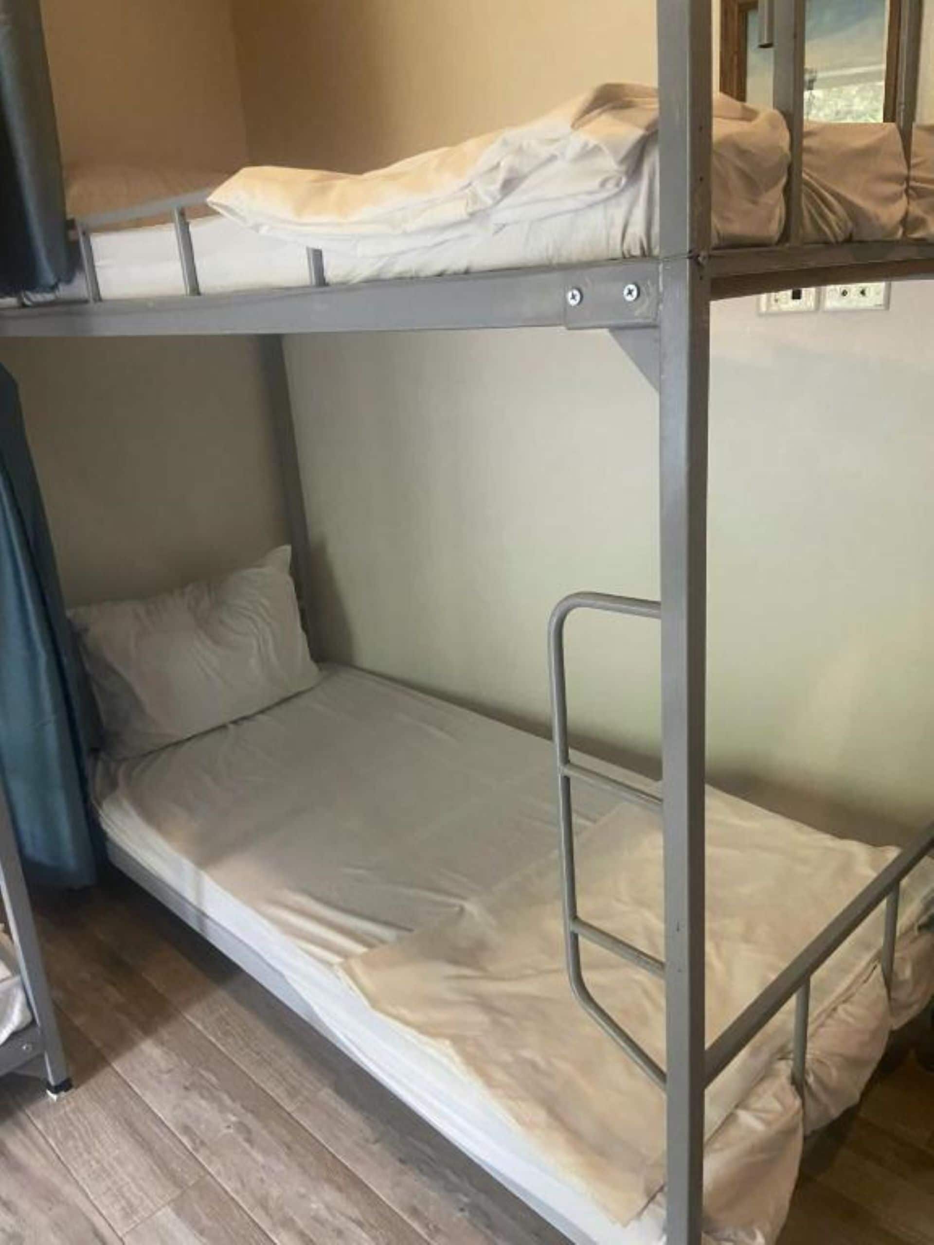 A bunk bed room with metal railings and a wooden floor.