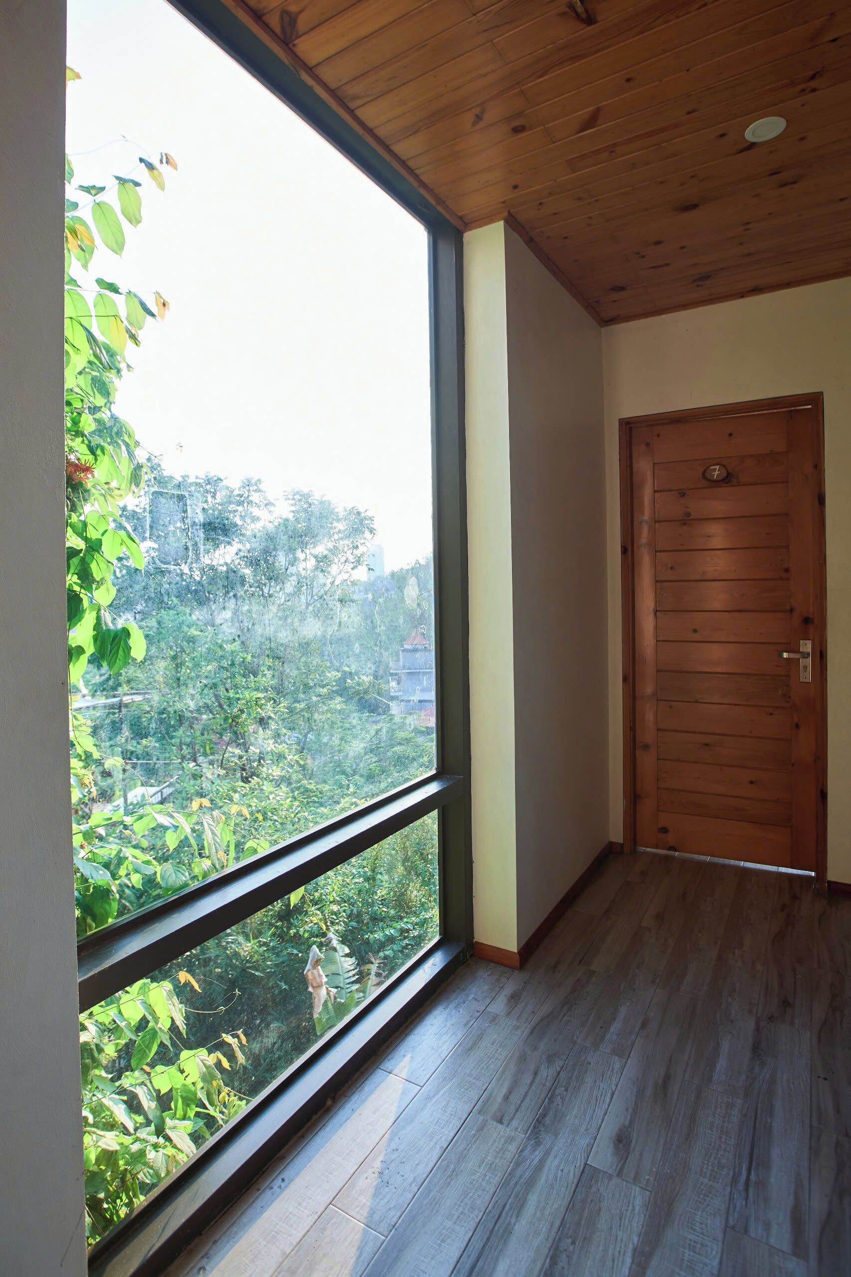 A room with a large window, wooden floor, and a wooden door.