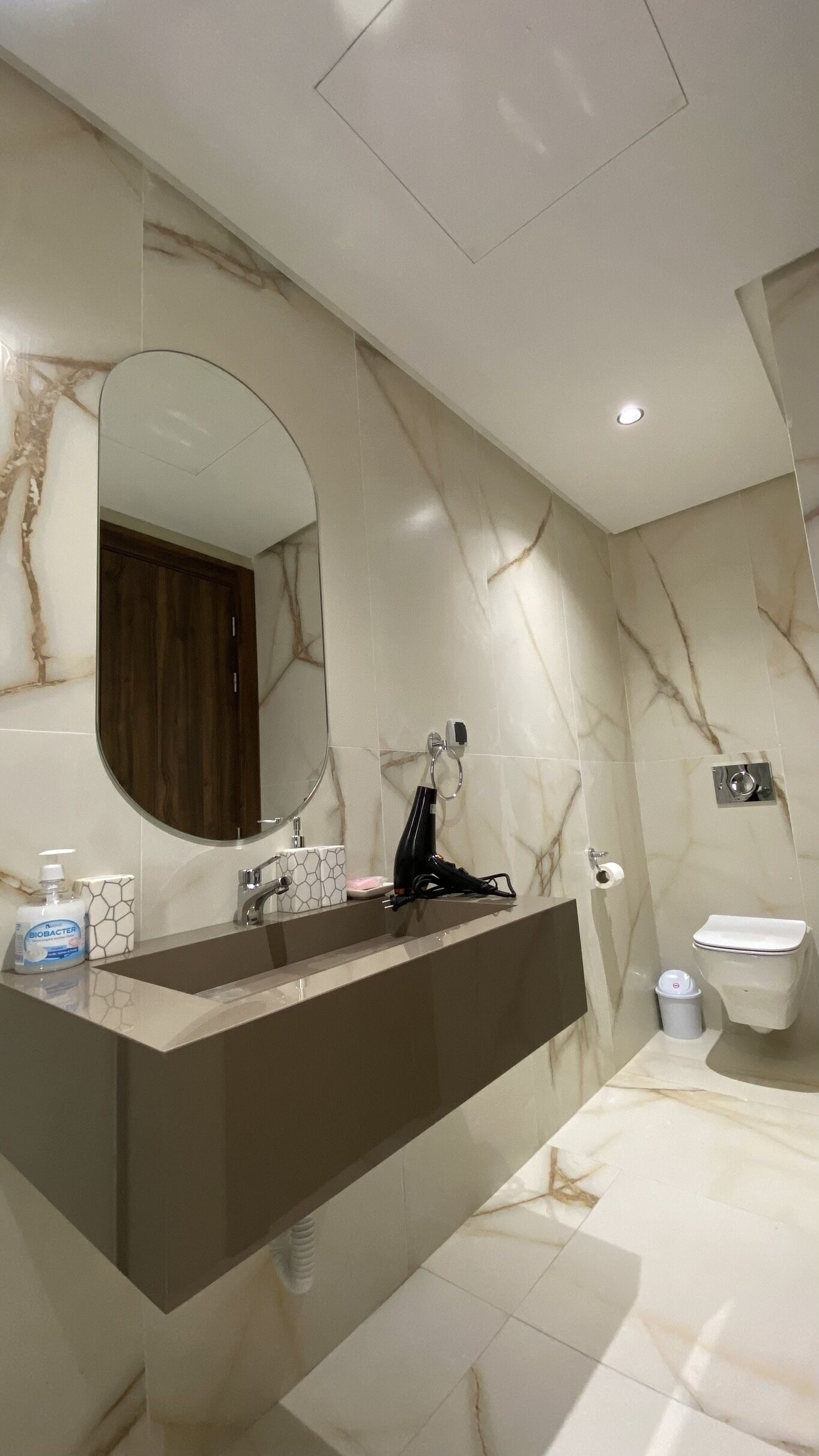 A modern bathroom with a marble vanity, a large mirror, a toilet, and a bidet.