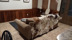 A living room with a brown couch, a plaid throw blanket, a wooden floor, a lamp, and a door with a window. - Oma's Haus in Franklin - Near Franklin Ranch Baseball Fields! (Franklin)