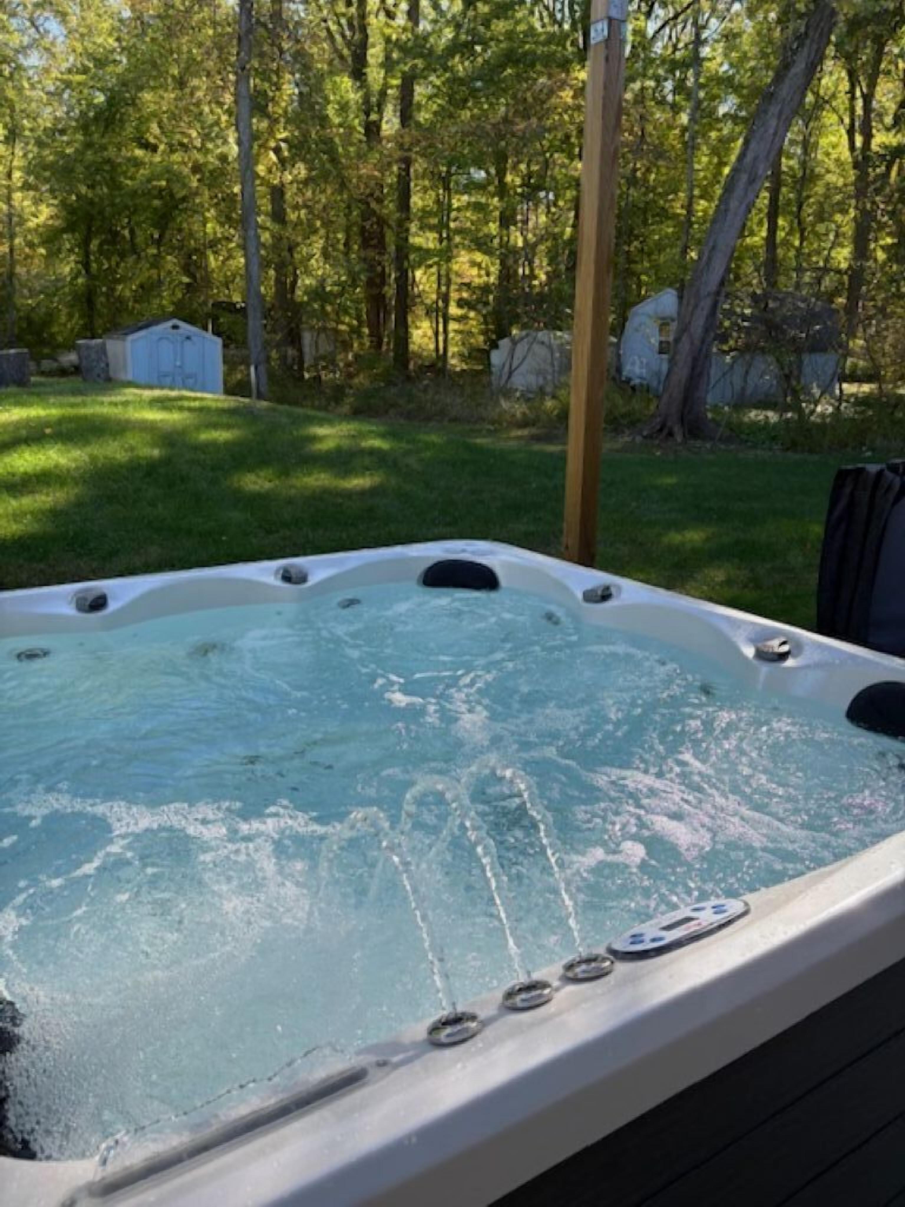 Un jacuzzi con chorros, rodeado de césped y árboles.