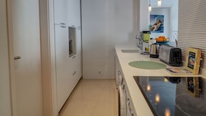 Eine moderne Küche mit weißen Schränken, einem eingebauten Backofen, einer Spüle, einem Toaster und einer Zeitschrift auf der Arbeitsplatte.