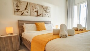 A neatly made bed with white and yellow bedding, a wooden headboard, and a bedside table with a lamp. - Diamond by Hello Homes Sitges (Sitges)