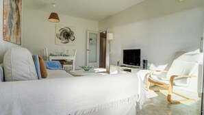 A modern hotel room with a large bed, a TV, a dining area, and a seating area. - Diamond by Hello Homes Sitges (Sitges)