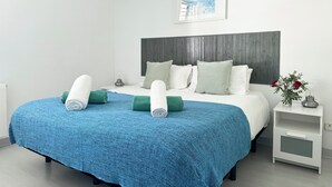 A neatly made bed with a blue textured bedspread, white pillows, and rolled towels. - Vistas Del Mar by Hello Homes Sitges (Sitges)