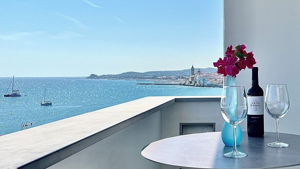 A balcony with a table, a bottle of wine, and a glass. - Vistas Del Mar by Hello Homes Sitges (Sitges)