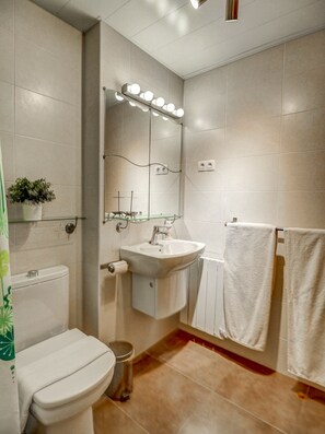 Ein modernes Badezimmer mit Toilette, Waschbecken und beleuchtetem Spiegel.