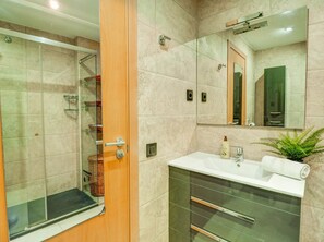 A modern bathroom with a glass shower enclosure, a white sink, and a large mirror. - Benito Apartment by Hello Homes Sitges (Sitges)