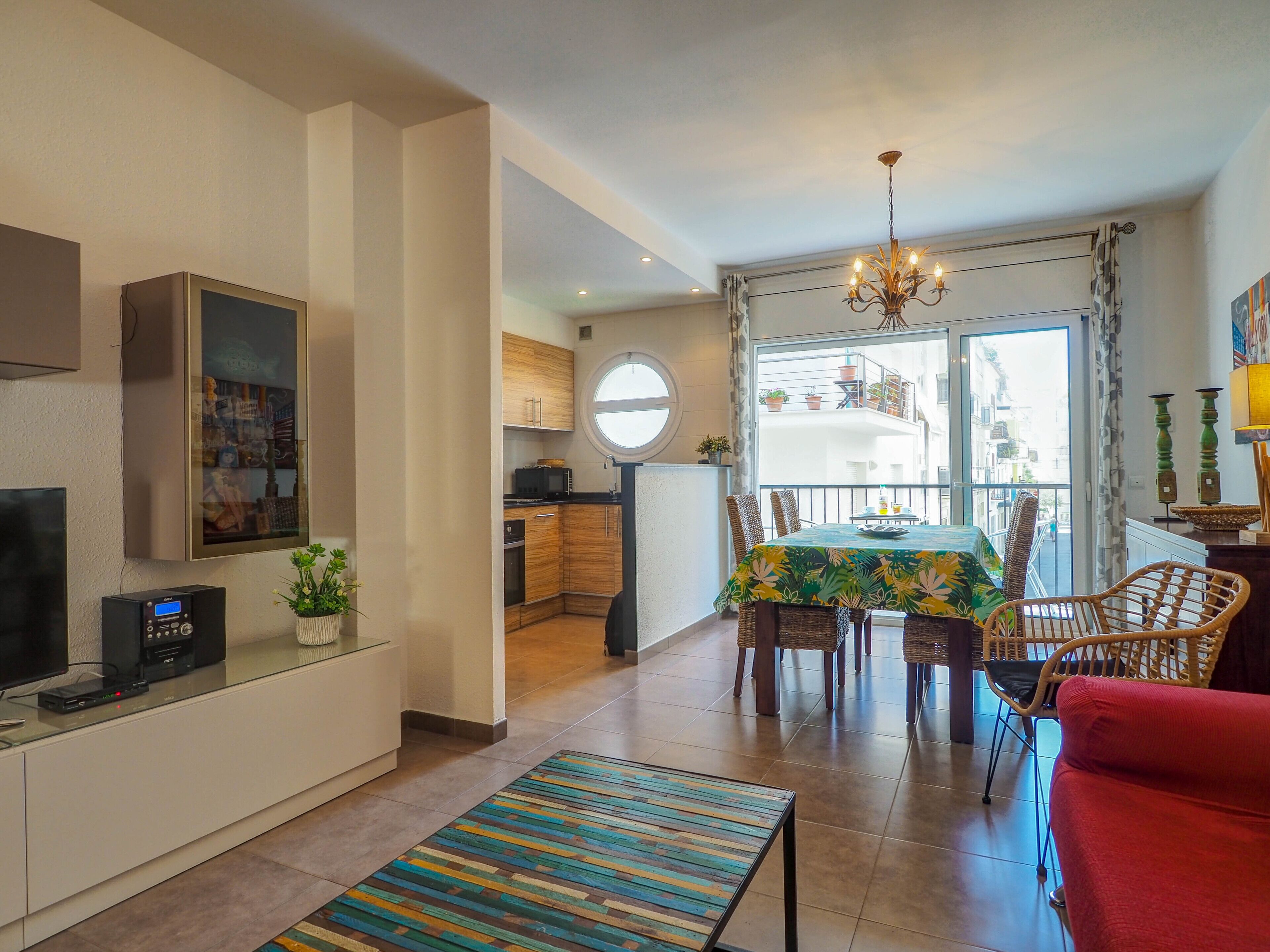 A modern apartment with a living area, dining space, kitchen, and a balcony with a view.