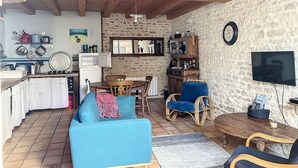 A cozy living area with a wooden ceiling, a dining table, a sofa, and a television.