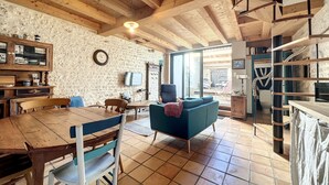 A rustic interior with a wooden dining table, chairs, a blue sofa, and a staircase leading to an upper level.