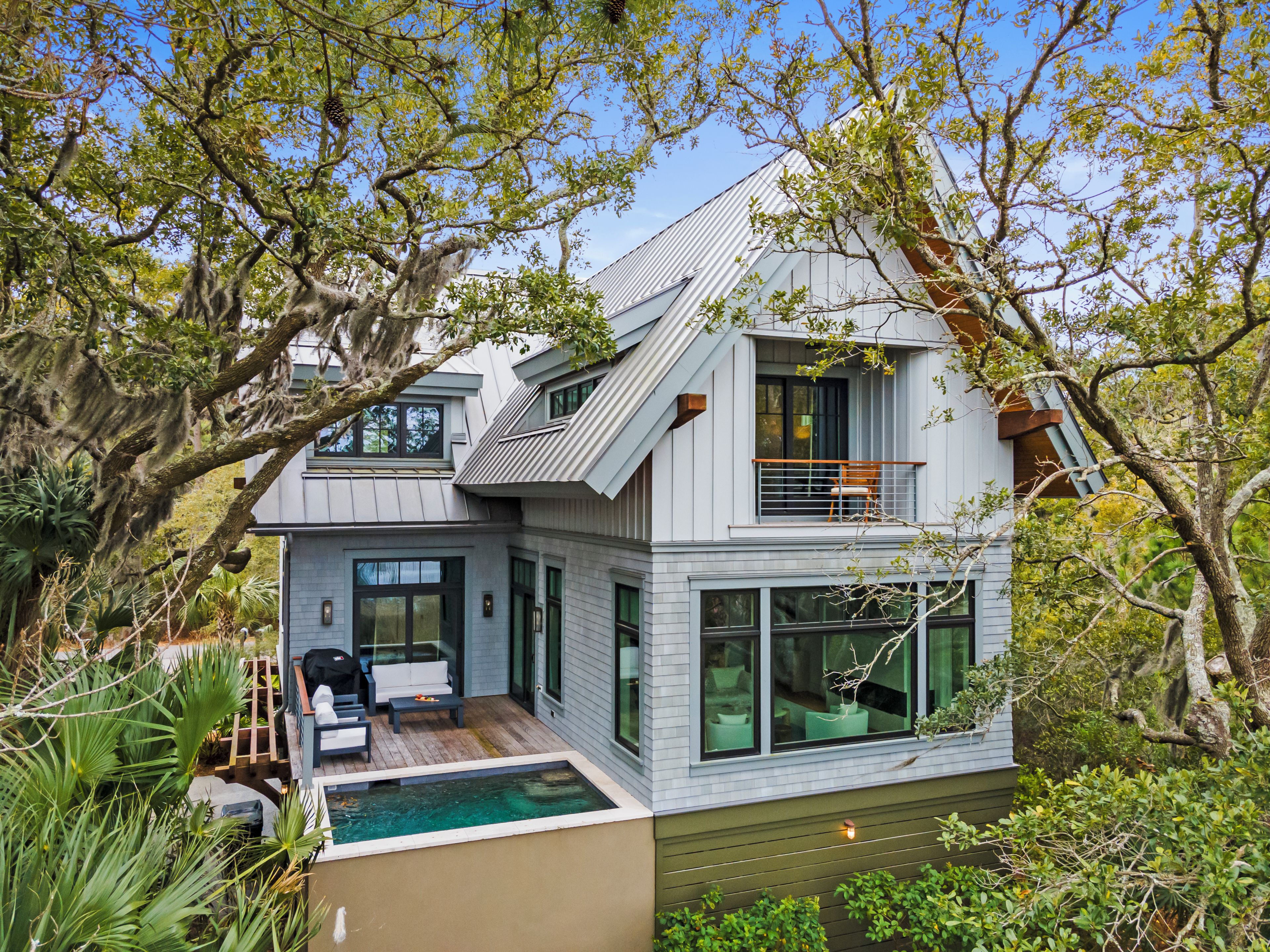Une maison moderne à deux étages, dotée d’un balcon, d’une petite terrasse et d’une piscine.
