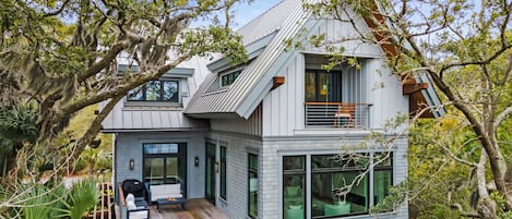 A modern two-story house with a balcony, a small deck, and a swimming pool.