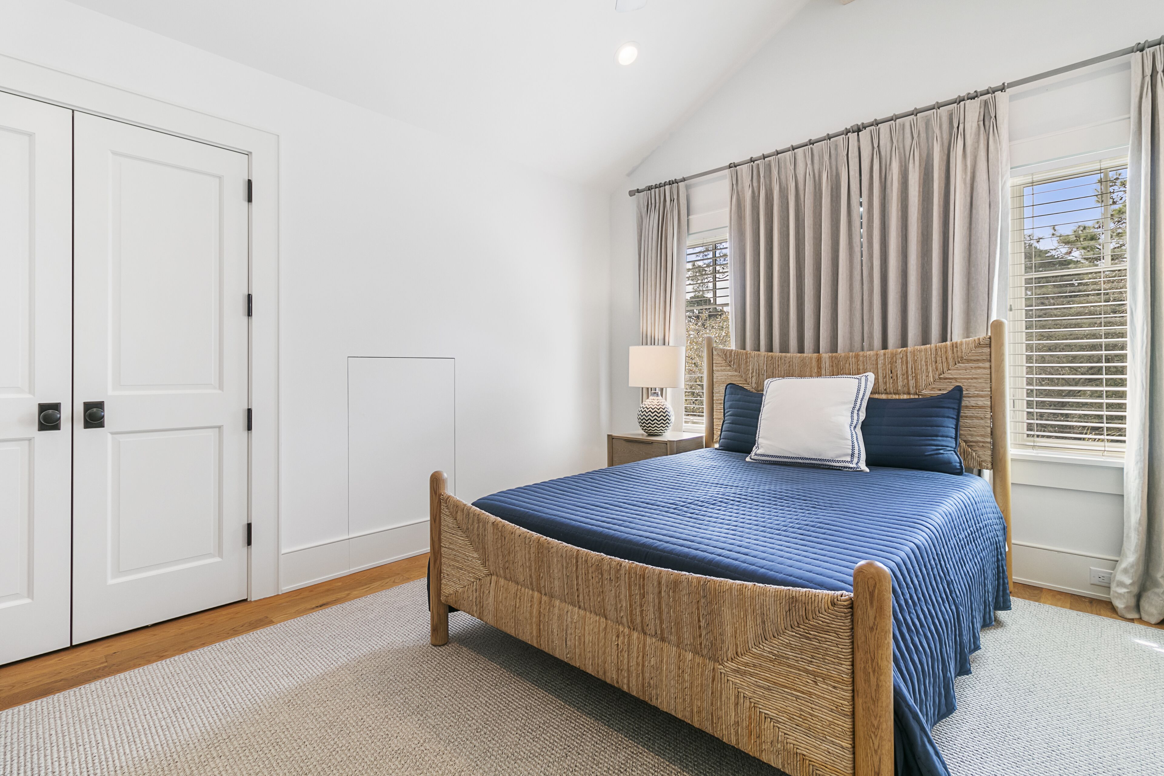 A bedroom with a bed, a nightstand, a lamp, and a window with curtains.