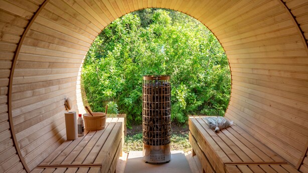 Una sauna con interior de madera, un sistema de calefacción central y vistas a la exuberante vegetación exterior.