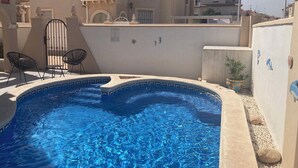 A swimming pool with a tiled edge, surrounded by a low wall and a gate. There are two chairs near the gate. - Detached villa with private pool, perfect for families and close to the beach (Orihuela Costa , Alicante)