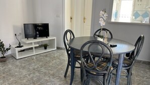 A dining area with a round table and chairs, a TV on a white stand, and a potted plant. - Detached villa with private pool, perfect for families and close to the beach (Orihuela Costa , Alicante)