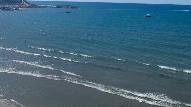 A beach with clear blue water, waves, and a distant rocky coastline. - Detached villa with private pool, perfect for families and close to the beach (Orihuela Costa , Alicante)