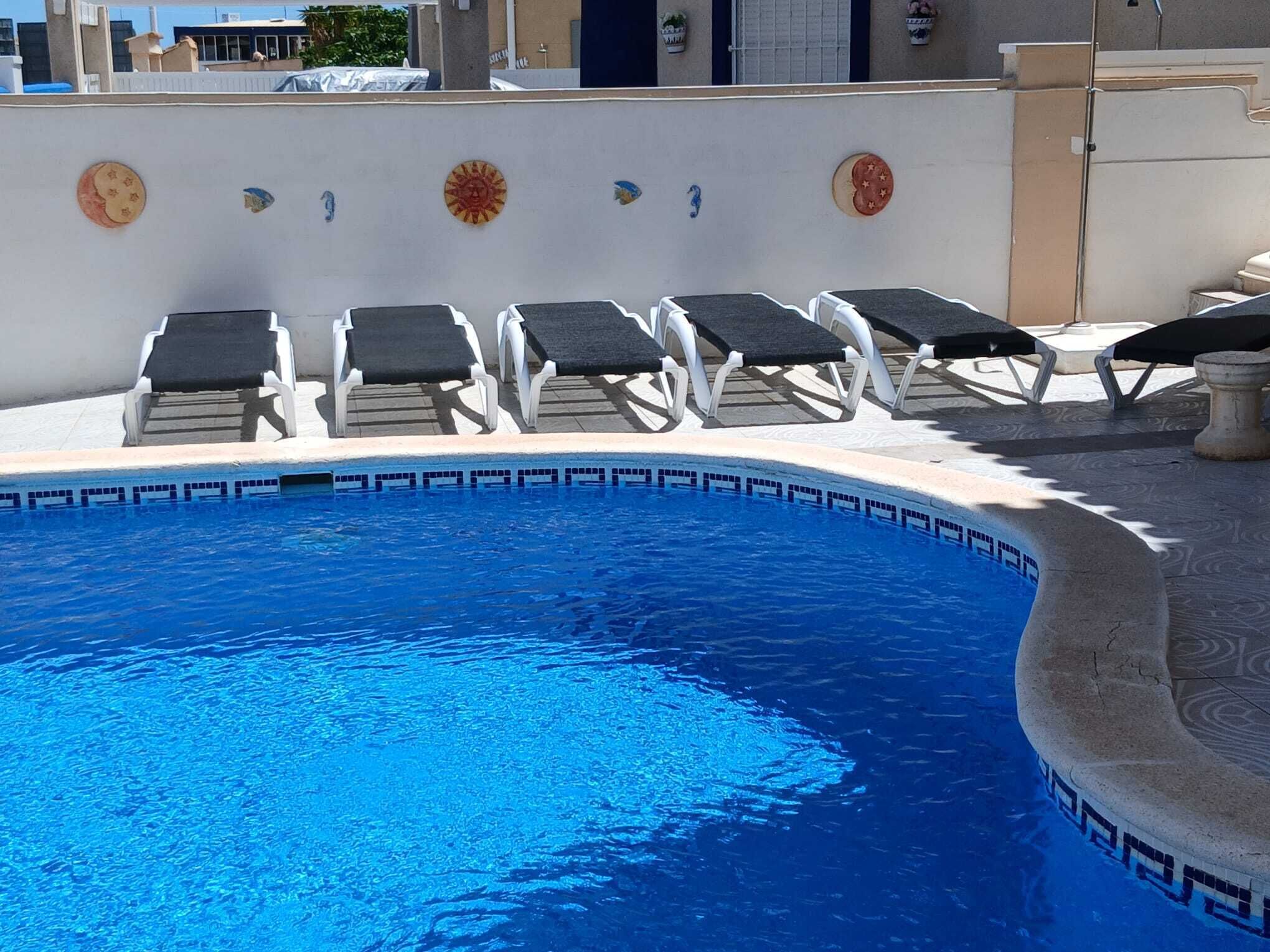 A swimming pool with lounge chairs and decorative tiles.