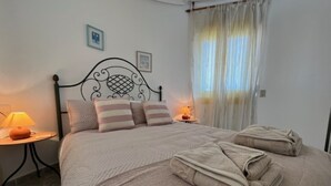 A neatly made bed with striped pillows, a bedside lamp, and a folded towel on the floor. - Detached villa with private pool, perfect for families and close to the beach (Orihuela Costa , Alicante)
