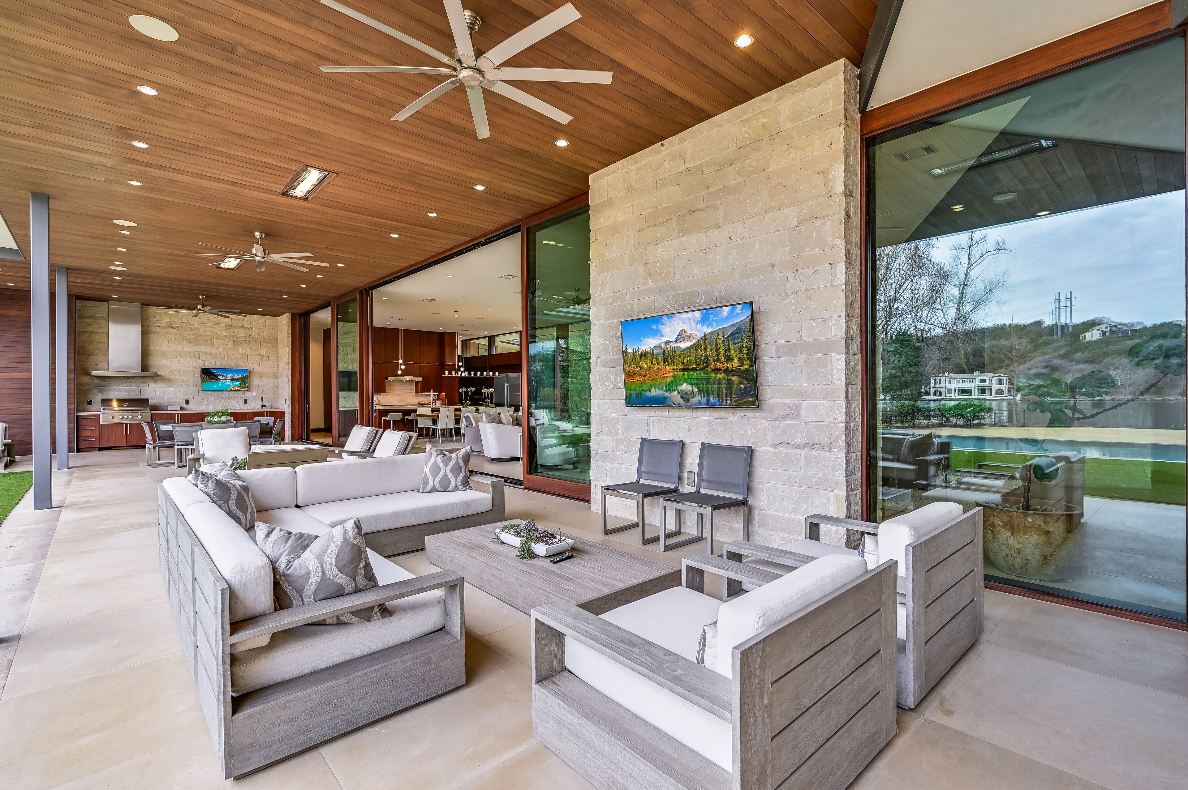 A modern living room with a large TV, comfortable seating, and a view of the outdoors.