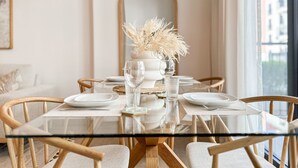 A dining table set with white plates, clear glassware, and a vase with dried flowers. - HiGuests - La Rive 2 (Dubai)