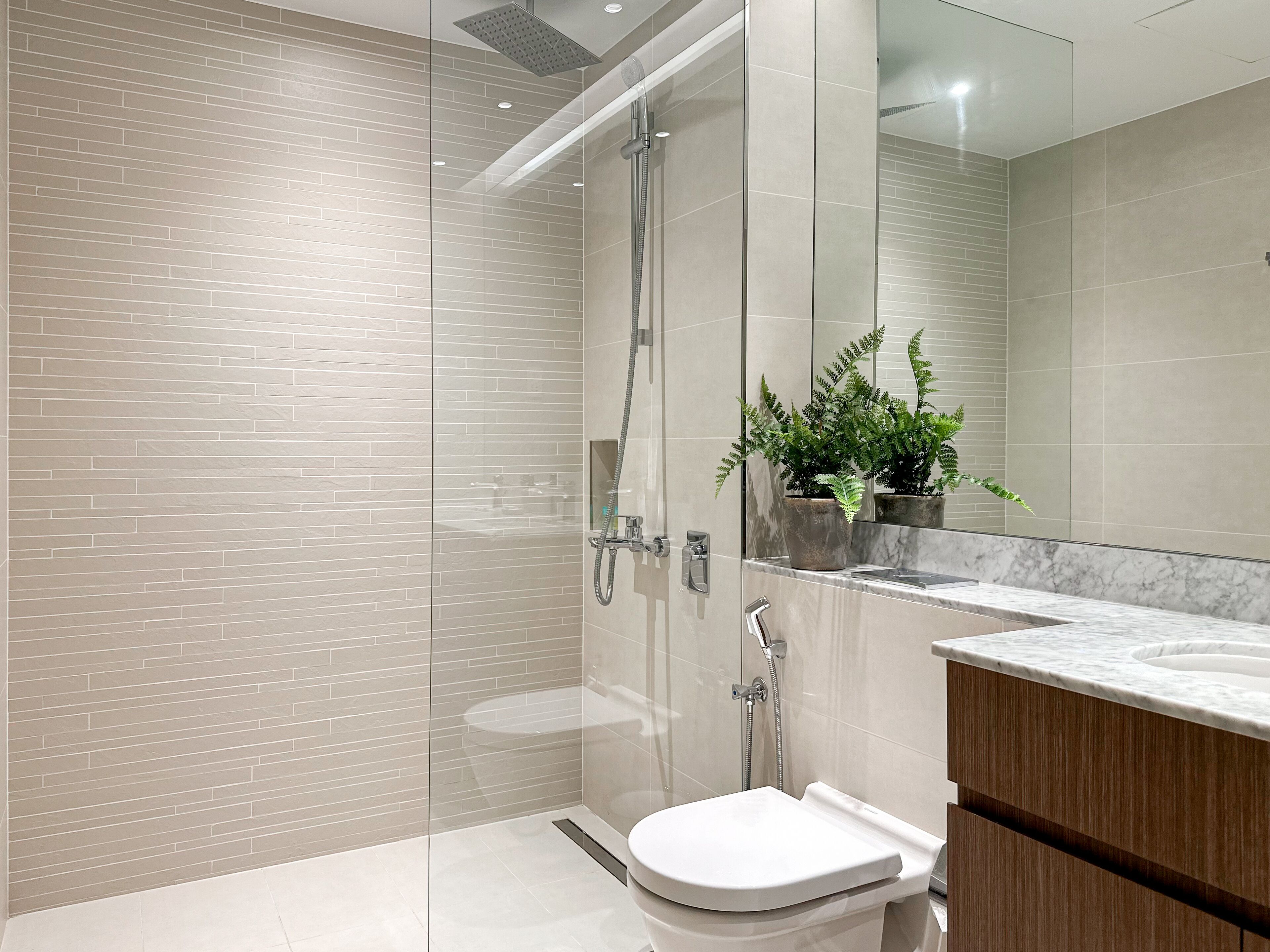 Une salle de bain moderne avec une douche à parois de verre, un lavabo en marbre et des toilettes.