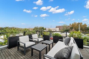 Una terrazza sul tetto con arredi da esterno, tra cui un divano e poltrone, e vista sulla città.