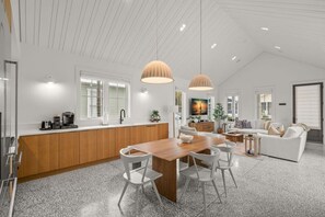 A modern kitchen with a wooden island, white chairs, and pendant lighting.