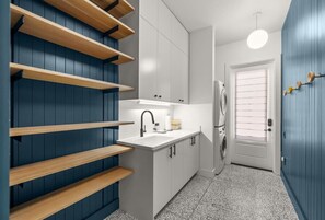 A compact kitchen with built-in shelves, a sink, and a washing machine.