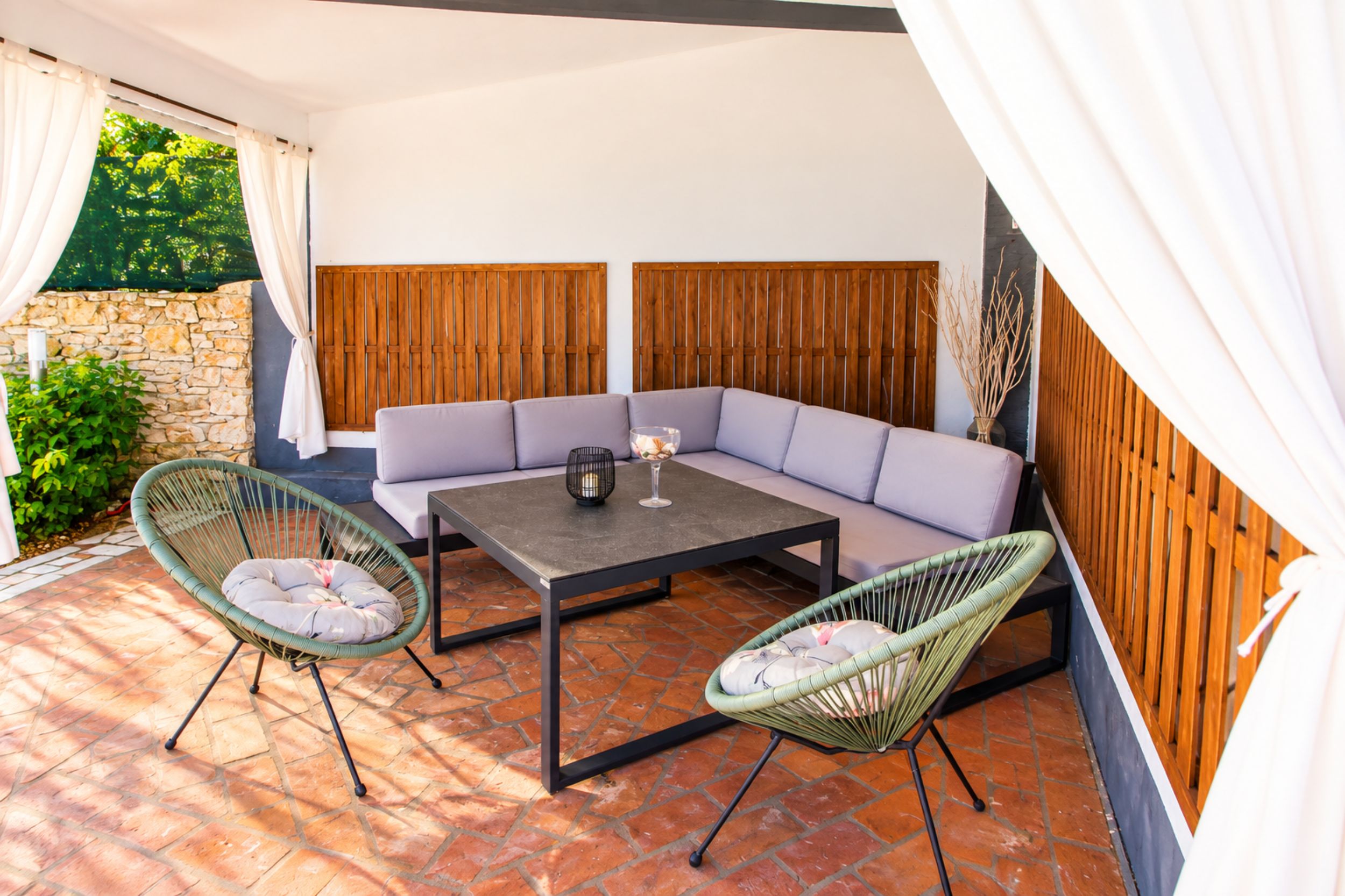 Un espacio al aire libre con sofá, dos sillones y una mesa.