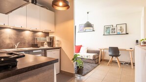 Une cuisine moderne équipée d’un four encastré, d’une machine à café et d’un lave-vaisselle. On y trouve également un coin repas avec une table et des chaises, ainsi qu’un canapé.