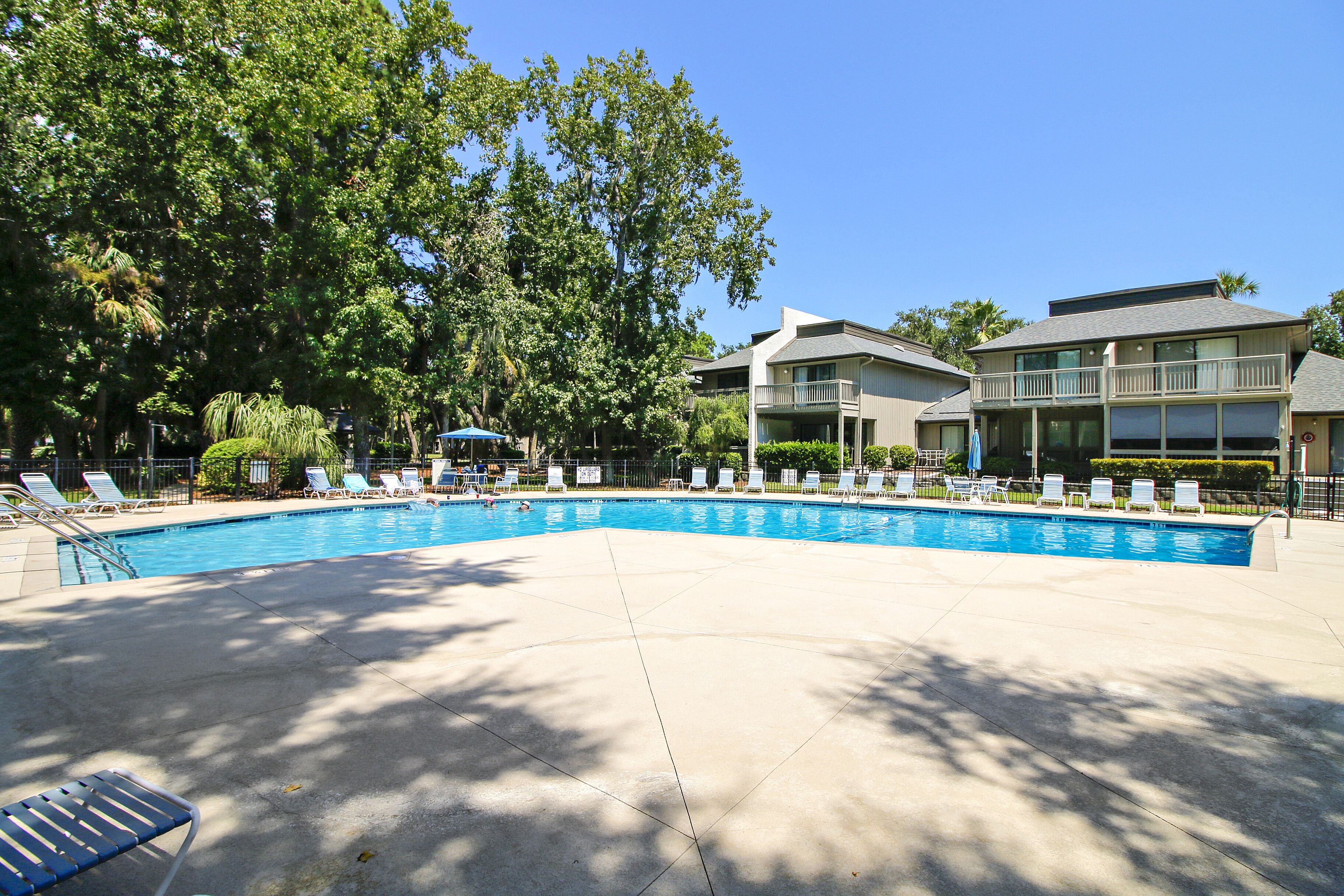 A swimming pool with lounge chairs and a building with balconies.