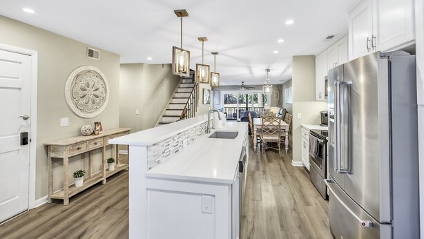 A modern kitchen with white cabinetry, a central island, stainless steel appliances, and pendant lighting.