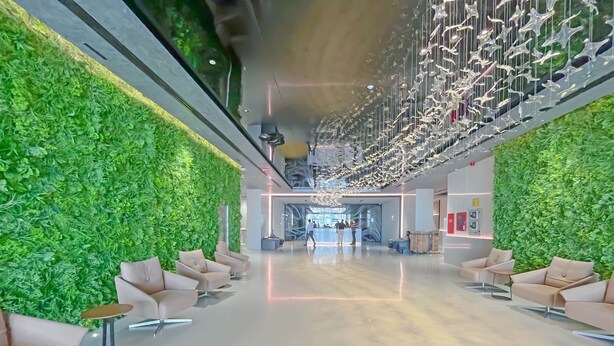 A modern lobby with green walls, seating areas, and a reception desk.