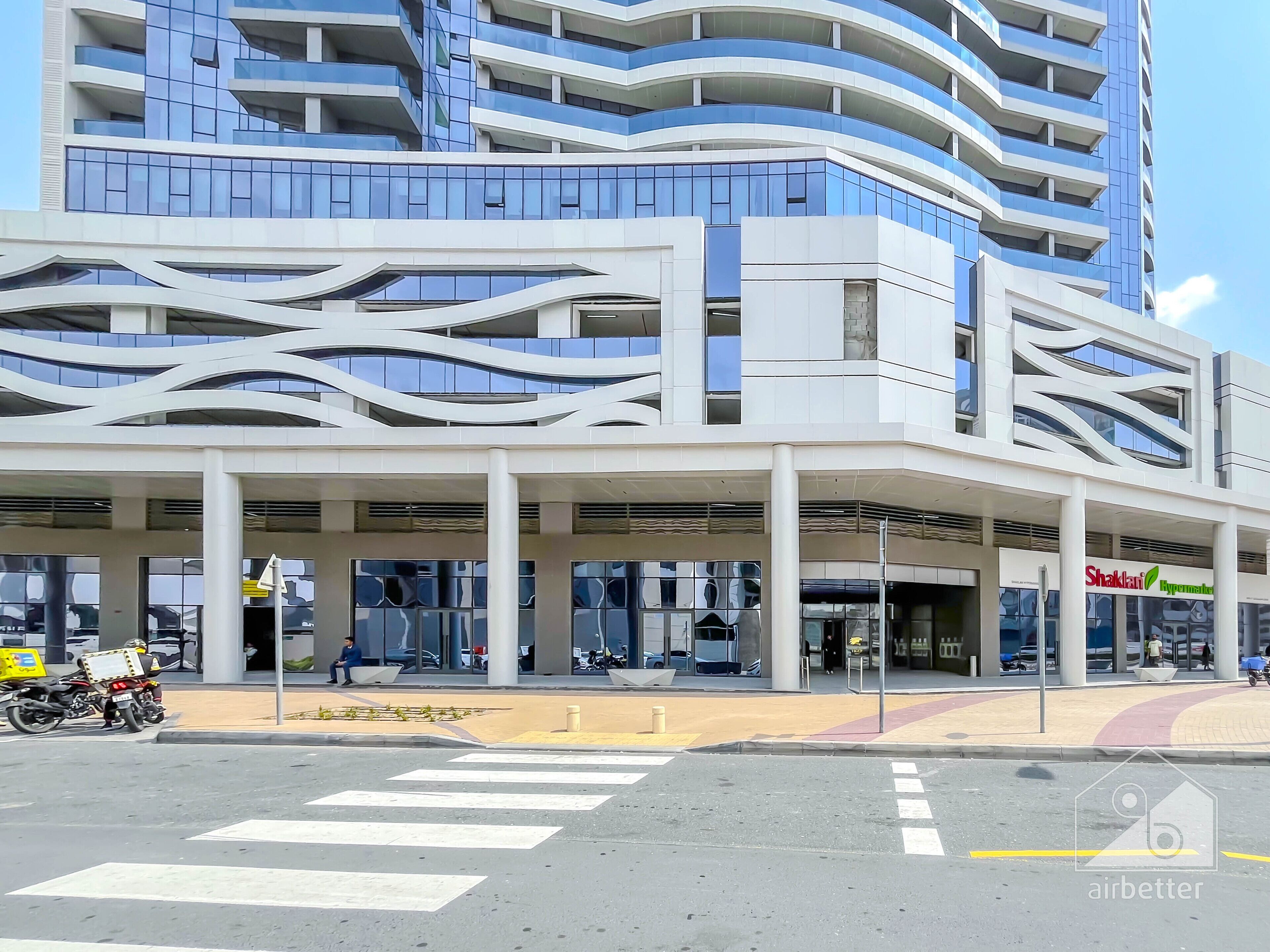 Een modern gebouw met een uniek architectonisch ontwerp, gekenmerkt door gebogen balkons en een overdekt entreegebied.