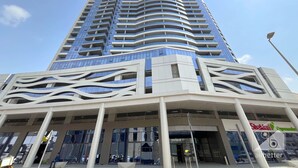 A modern high-rise building with a curved facade and a lower section featuring a wavy architectural design.