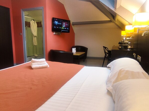 A hotel room with a bed, a desk, a chair, a TV mounted on the wall, and a bathroom visible through an open door. - Contact Hotel B&G (Limoges)