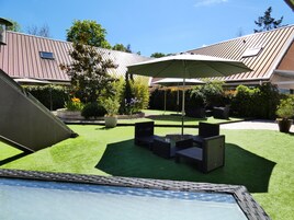 Un patio trasero con zona de terraza, pérgola y césped.
