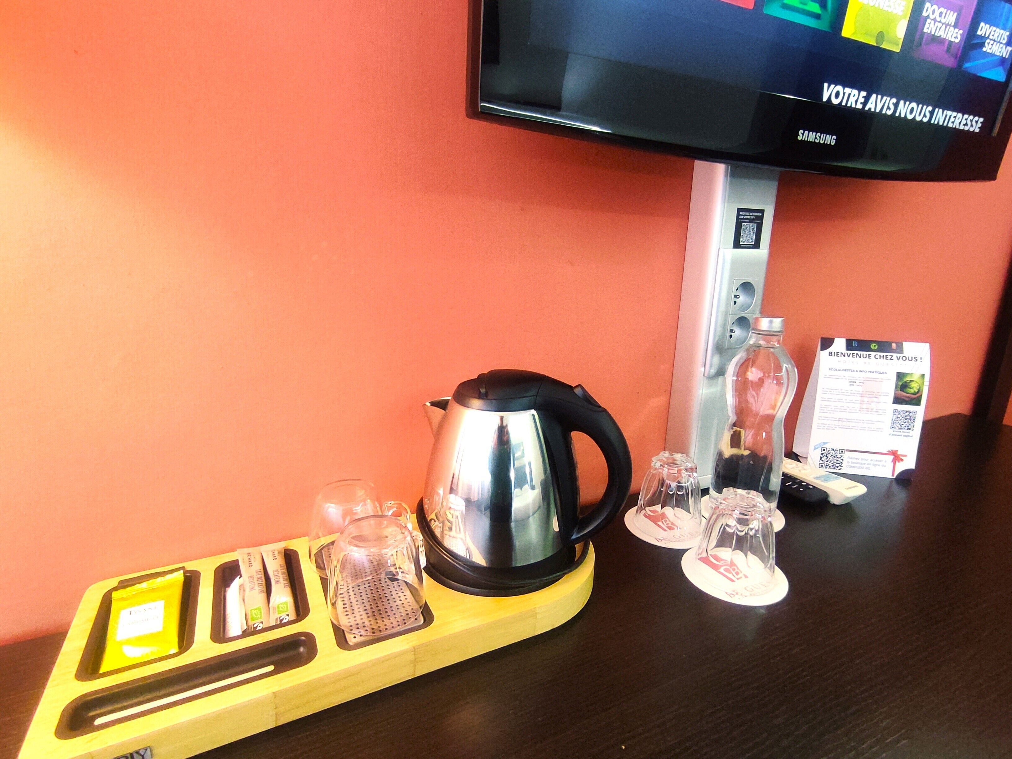 A kitchen area with a kettle, glasses, and a tray with utensils.