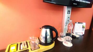 A kitchen area with a kettle, glasses, and a tray with utensils.