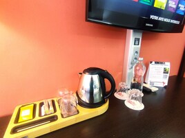 Una zona de cocina con hervidor, vasos y una bandeja con utensilios.