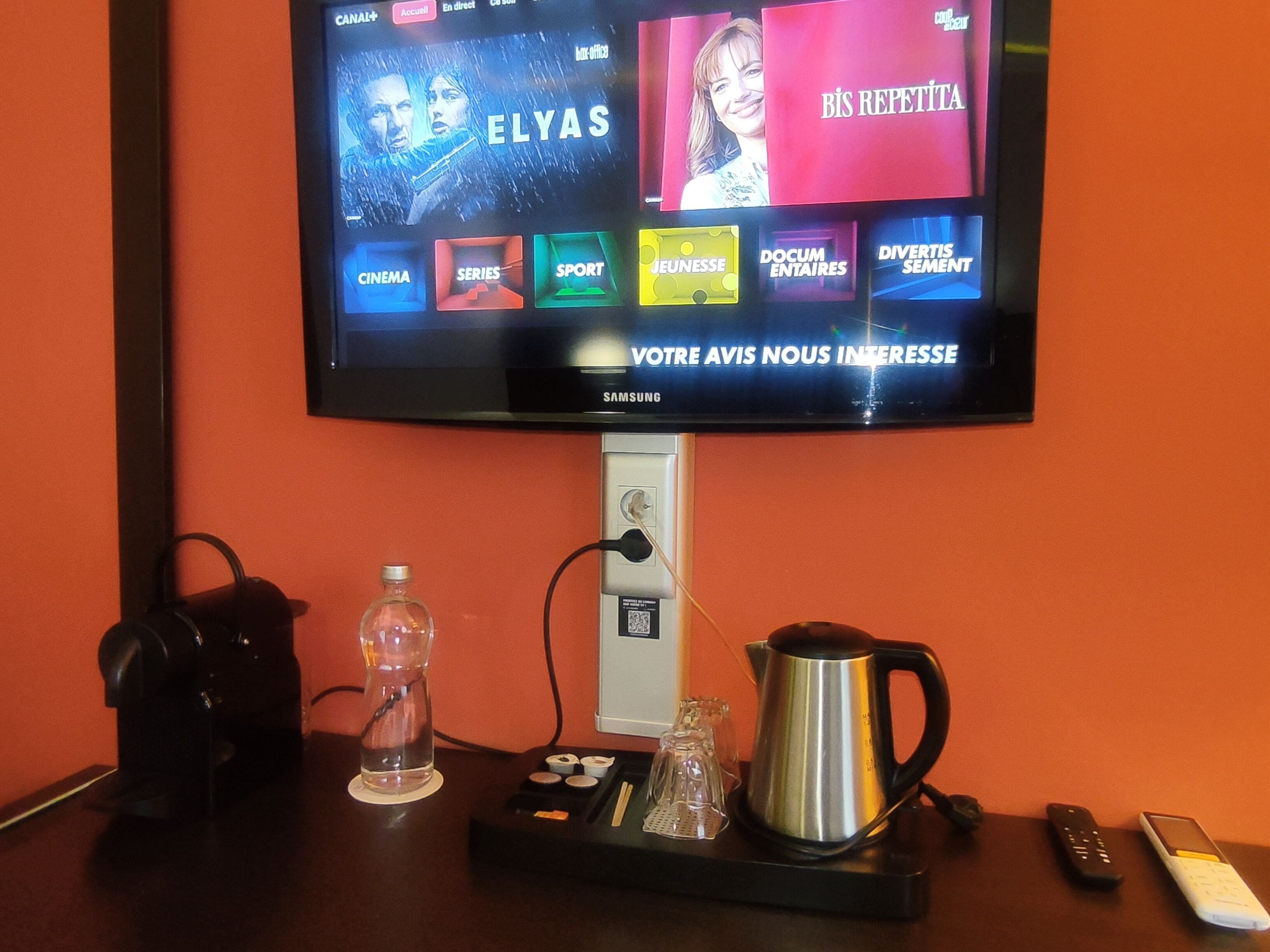 A television mounted on a wall displaying various channels and a Samsung logo.
